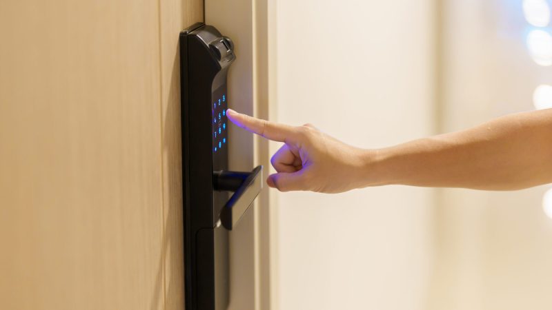 Hand press PIN number for smart digital door lock while open or close the door at home or apartment. NFC Technology, Fingerprint scan, keycard, smartphone and contactless lifestyle concepts