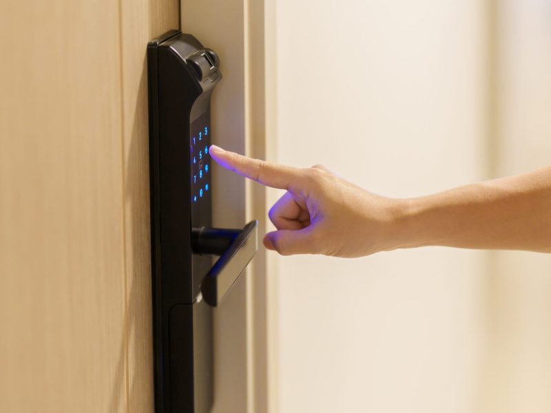 Hand press PIN number for smart digital door lock while open or close the door at home or apartment. NFC Technology, Fingerprint scan, keycard, smartphone and contactless lifestyle concepts