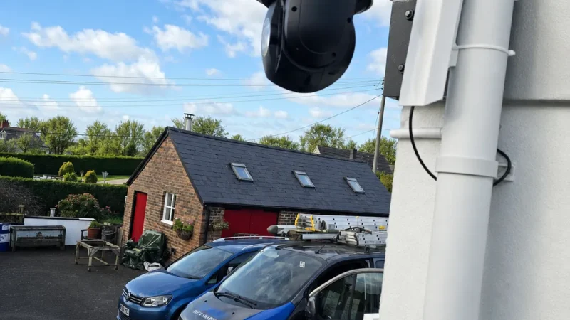 Hikvision pan-tilt CCTV camera mounted on a commercial property exterior.